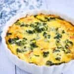 caramelized onion and kale quiche in a white baking dish with tea towel in background
