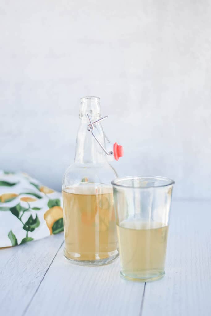 grolsch bottle of flavor water kefir with a glass and lemon tea towel 