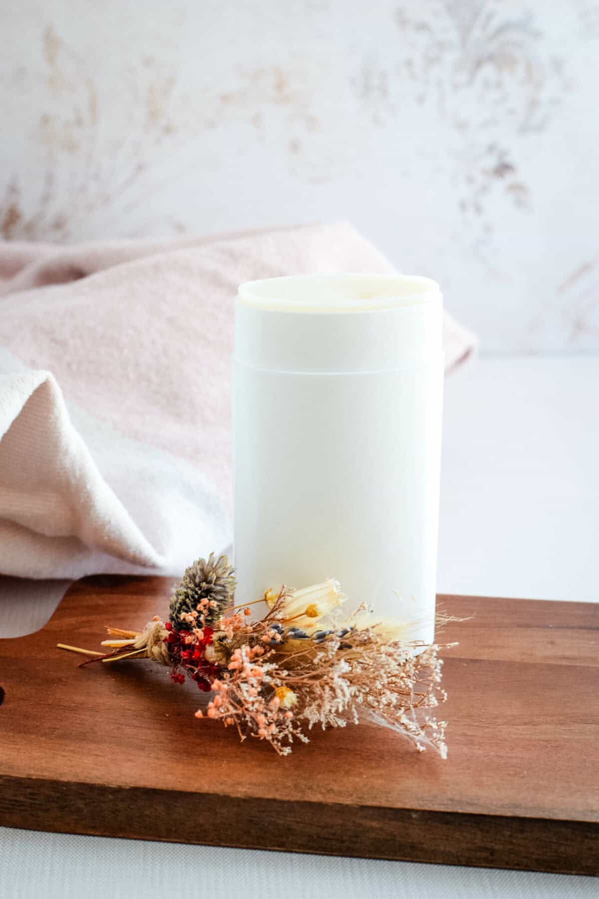 homemade natural deodorant in a white container and standing on a wooden board. 