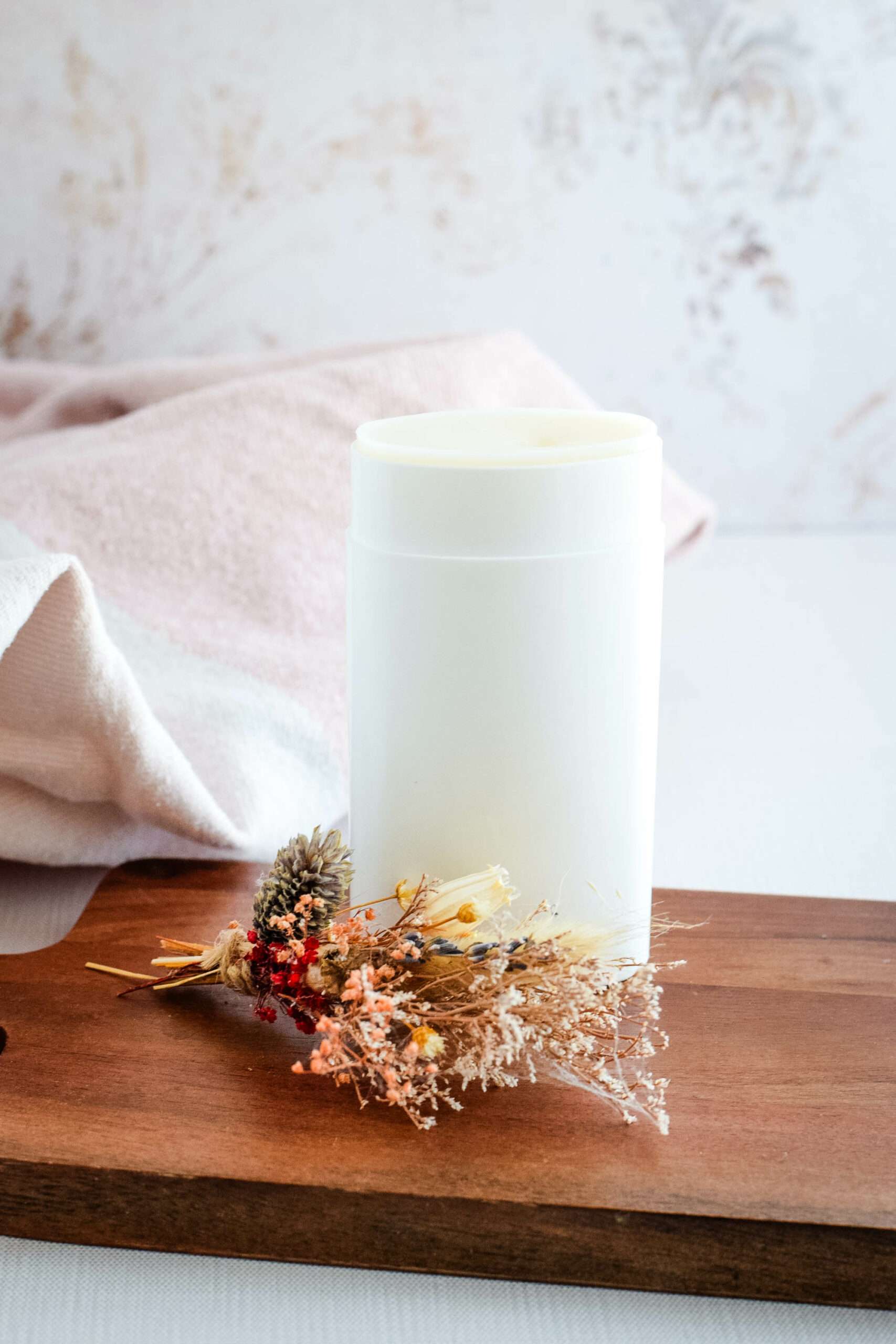 homemade natural deodorant in a white container and standing on a wooden board.