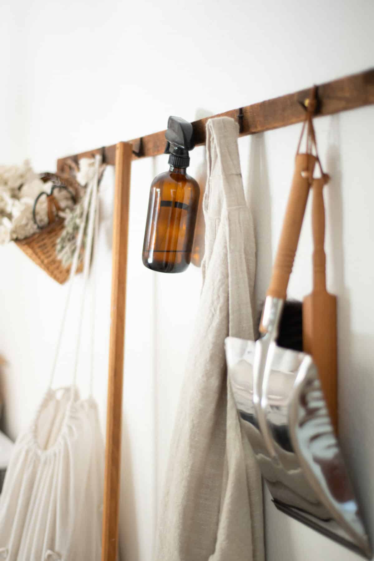 natural cleaning supplies, glass spray bottle hanging on hooks.