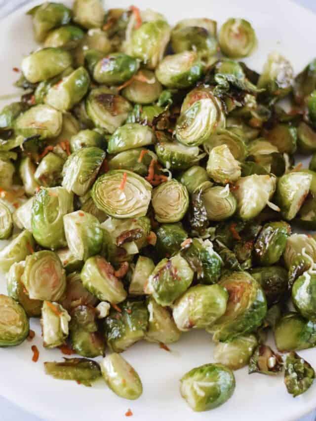 white platter of Roasted Brussels sprouts with a black spoon resting to the side.