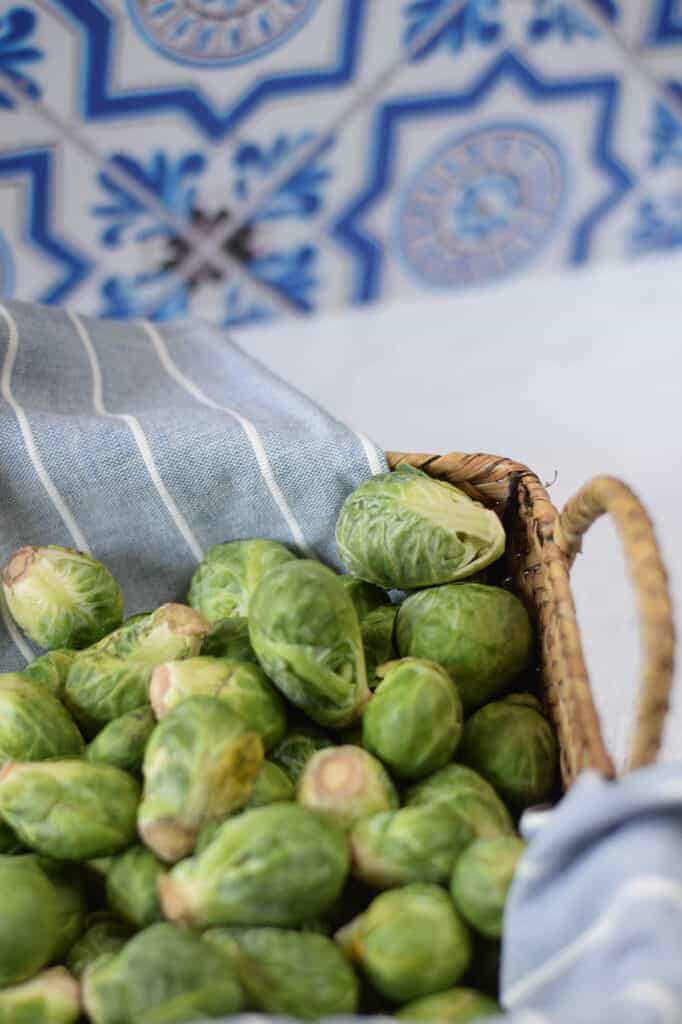 fresh Brussels sprouts in a basket with a blue tea towel