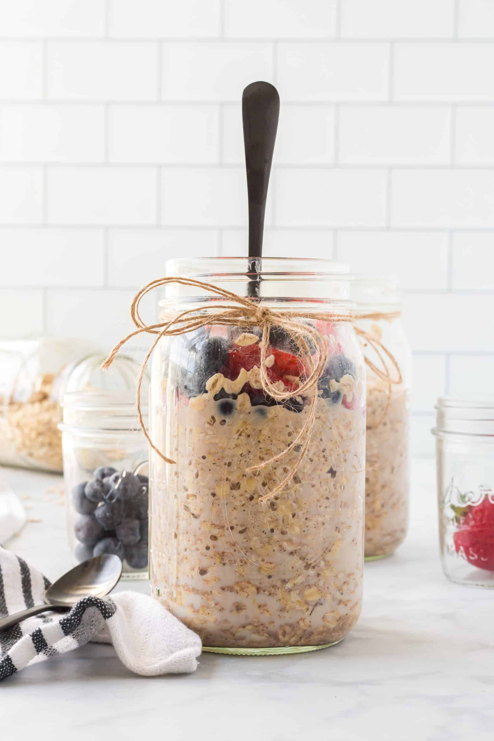 Mason jar filled with overnight oats and topped with fresh berries and black spoon 