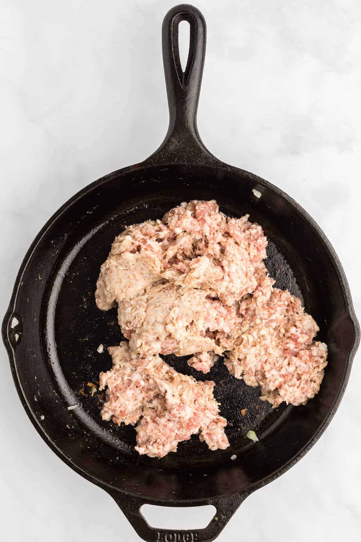 cooking the ground sausage in the cast iron skillet.