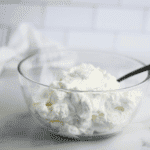 homemade maple whipped cream in a large bowl with a black serving spoon
