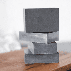 stack of charcoal soap bars on a wooden board