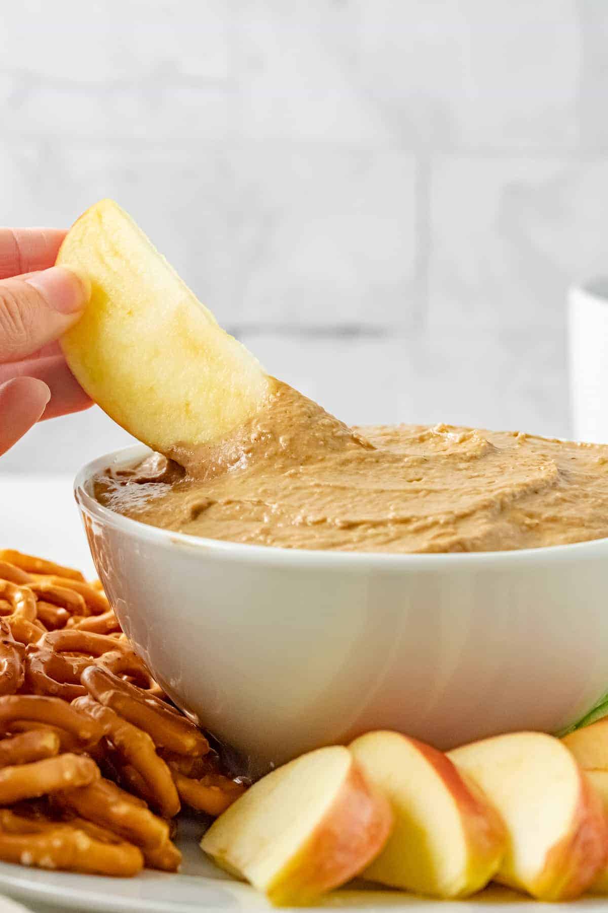 dipping an apple slice in to the gingerbread hummus on the platter
