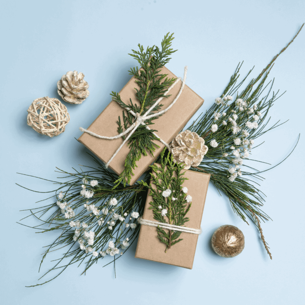 gifts wrapped with brown paper and Christmas greenery with a light blue background