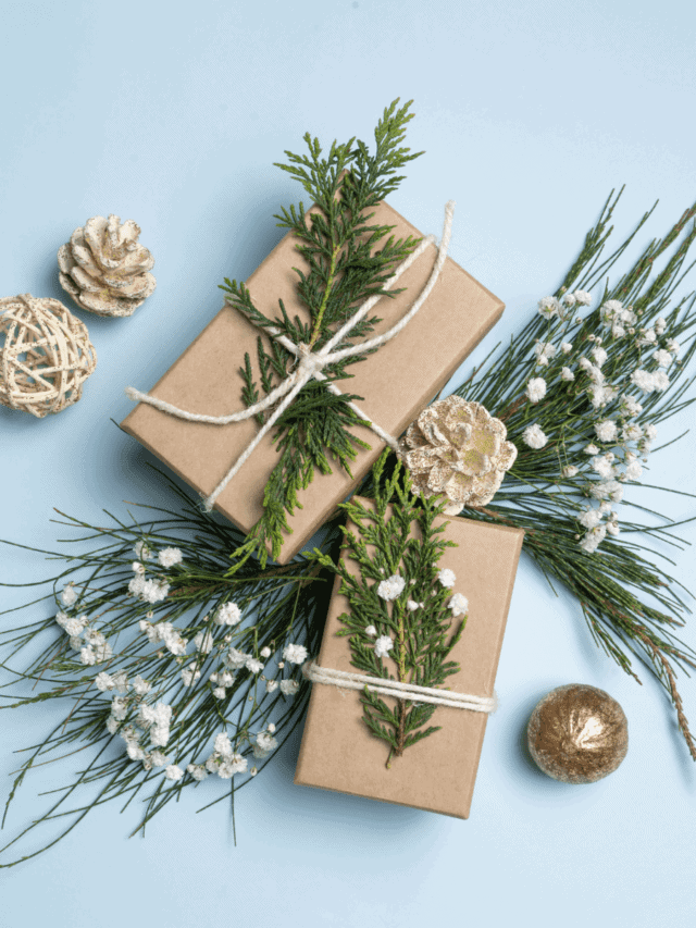 gifts wrapped with brown paper and Christmas greenery with a light blue background