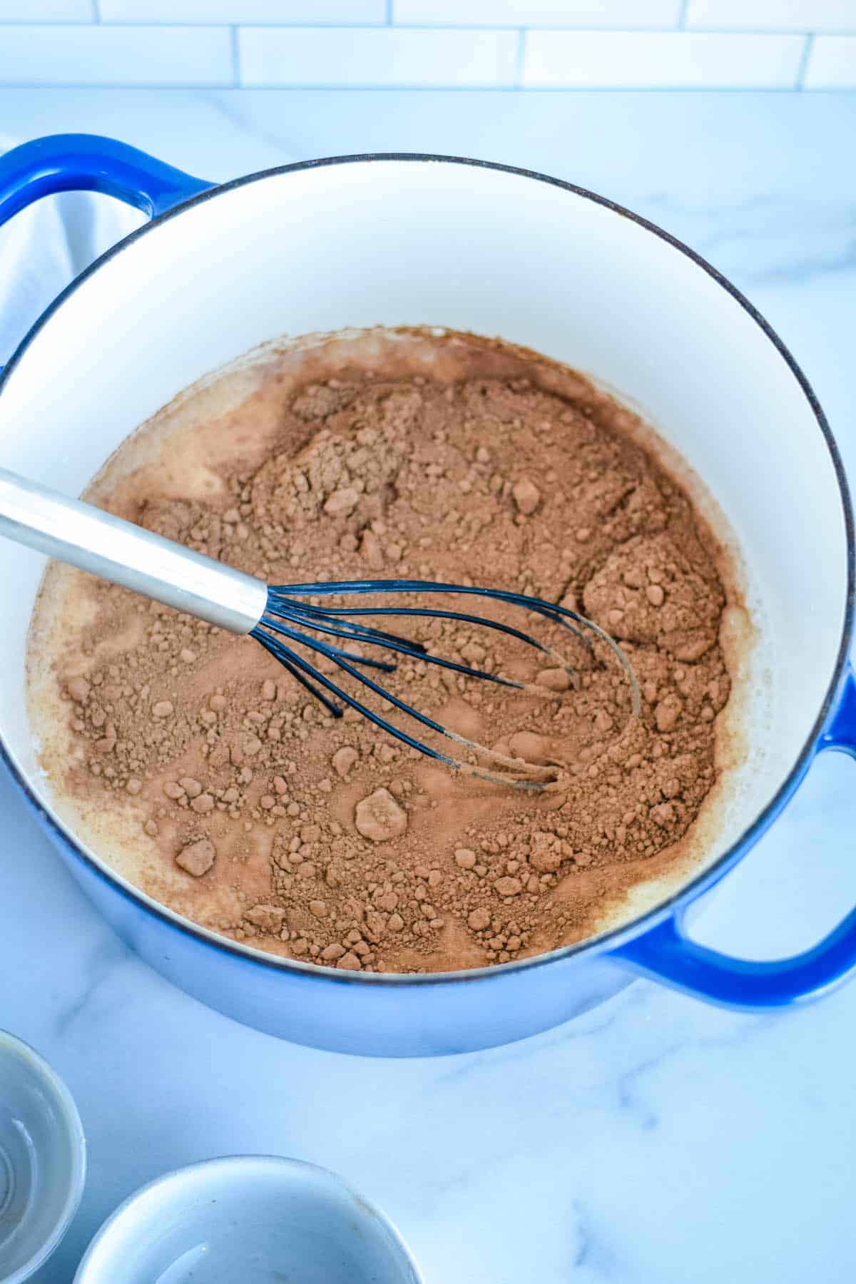 process shot of the hot chocolate in a blue pot with black and sliver whisk