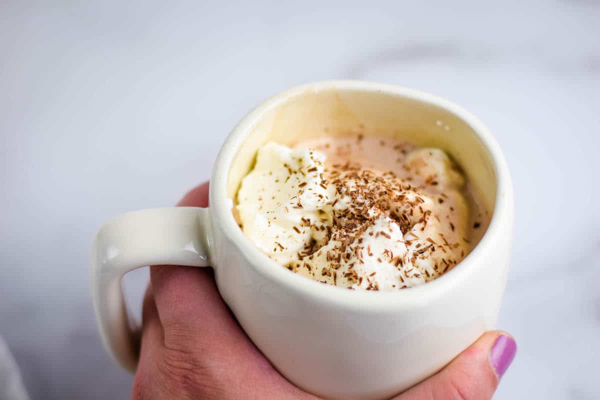 healthy hot chocolate in a white mug with homemade maple whipped cream and dark chocolate shavings on top