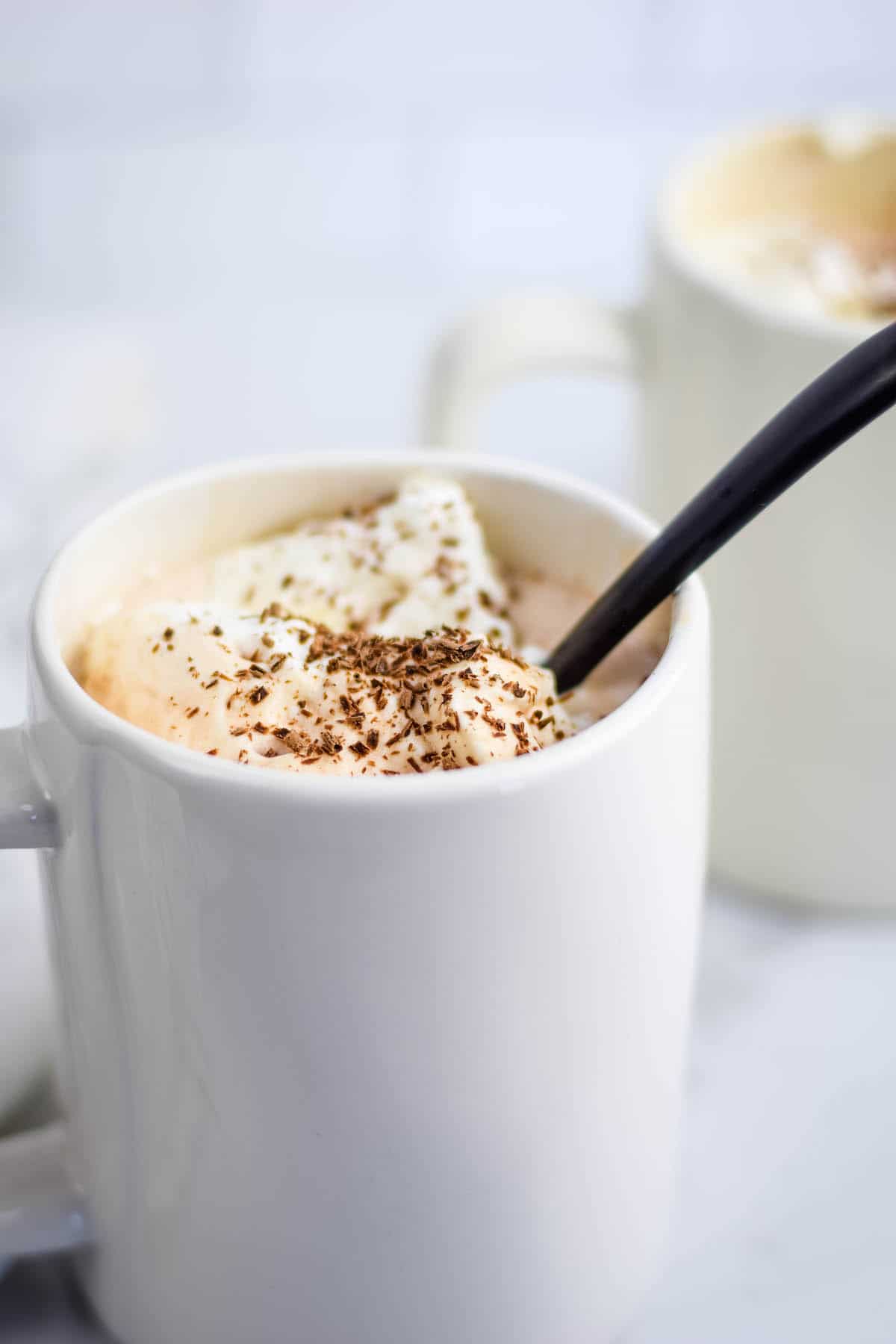 two white mugs of healthy hot chocolate with homemade whipped cream and chocolate shavings on top