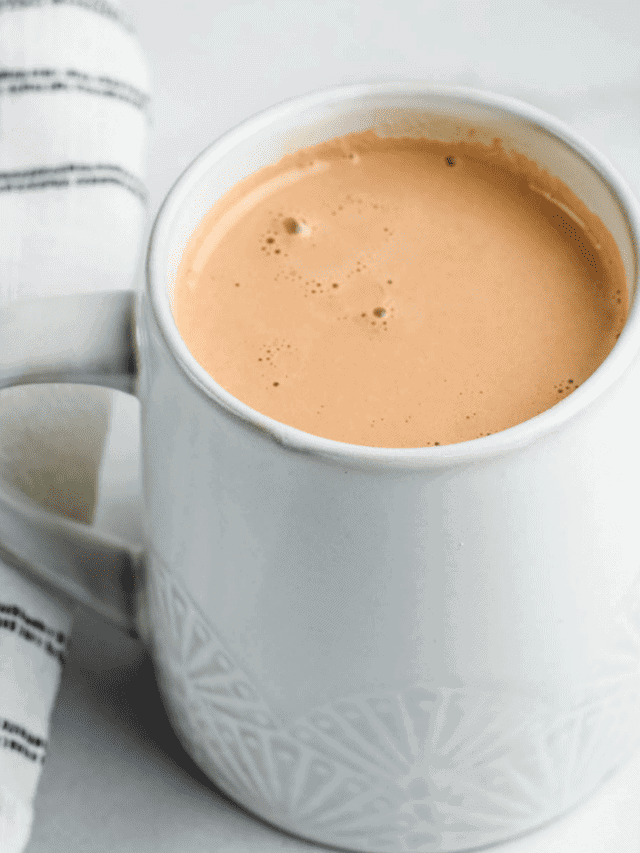 creamy & healthy hot chocolate in a white mug with a black and white striped tea towel beside it