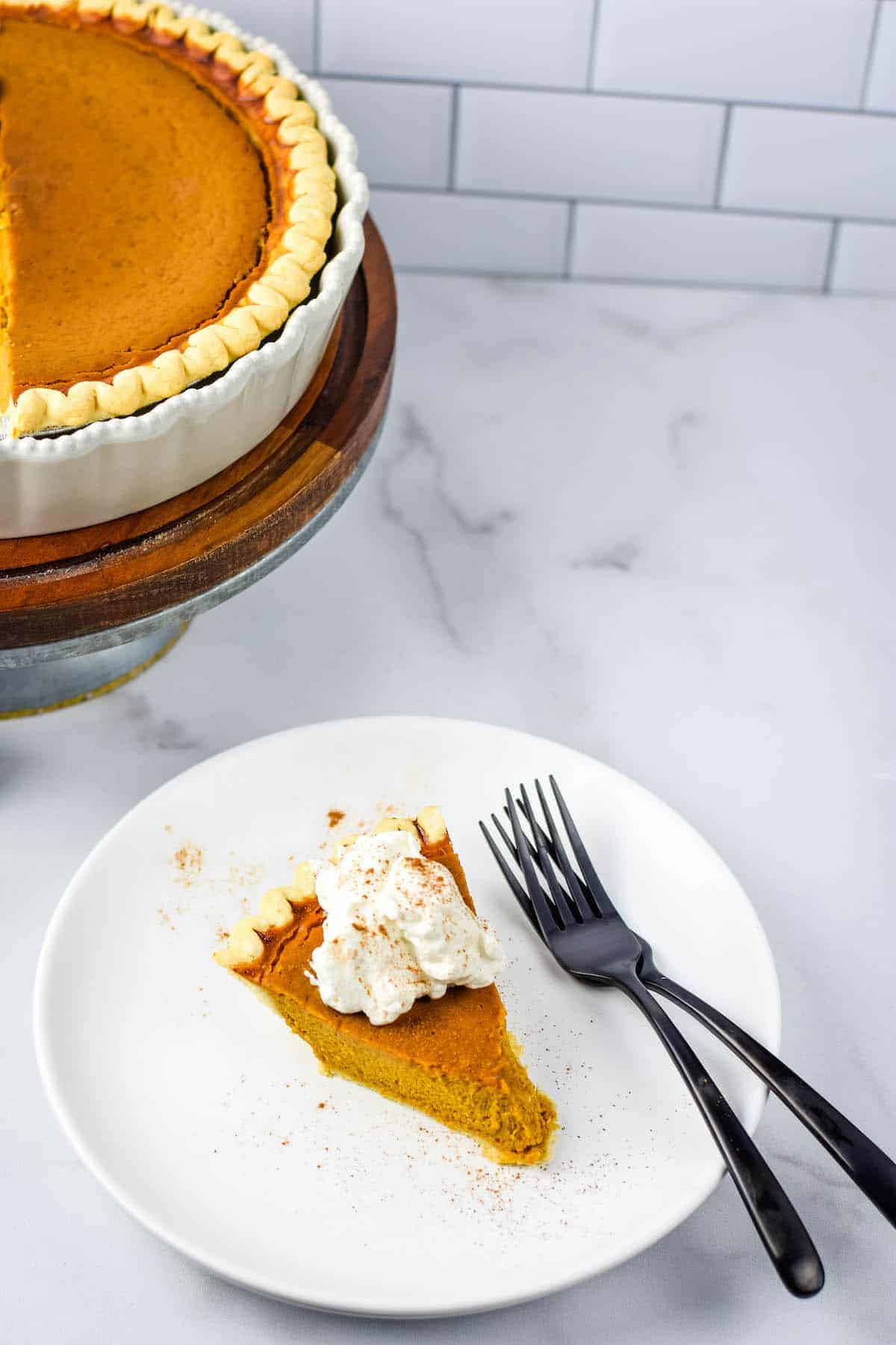 slice on healthy pumpkin pie on white plate with black forks