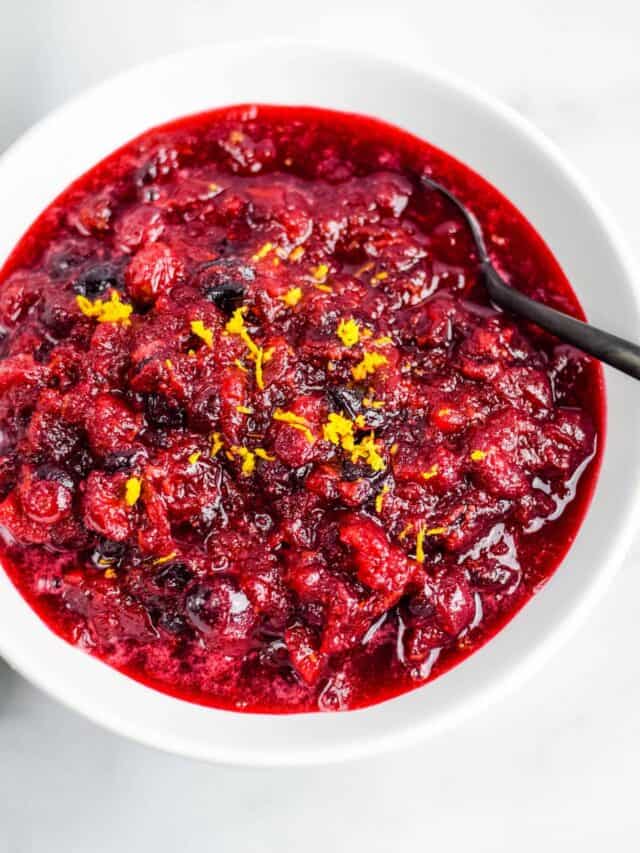 white bowl filled with healthy cranberry sauce and a black spoon to the side.