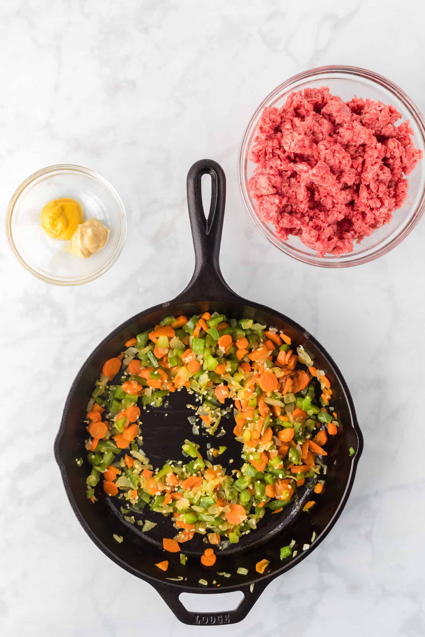 sautéed vegetables in the cast iron skillet with the meat in a bowl to the side