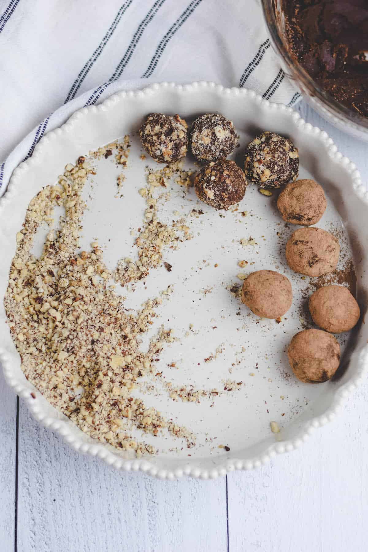 shallow white dish with chopped hazelnuts and rolled chocolate truffles