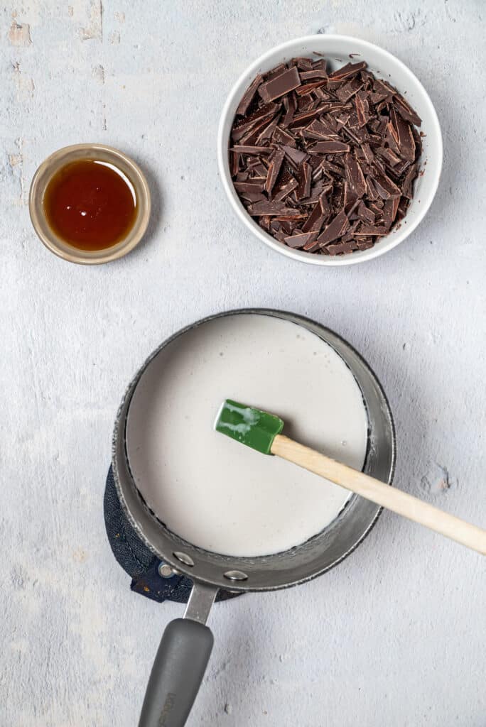 coconut cream in a small saucepan with spatula and chocolate in small bowls
