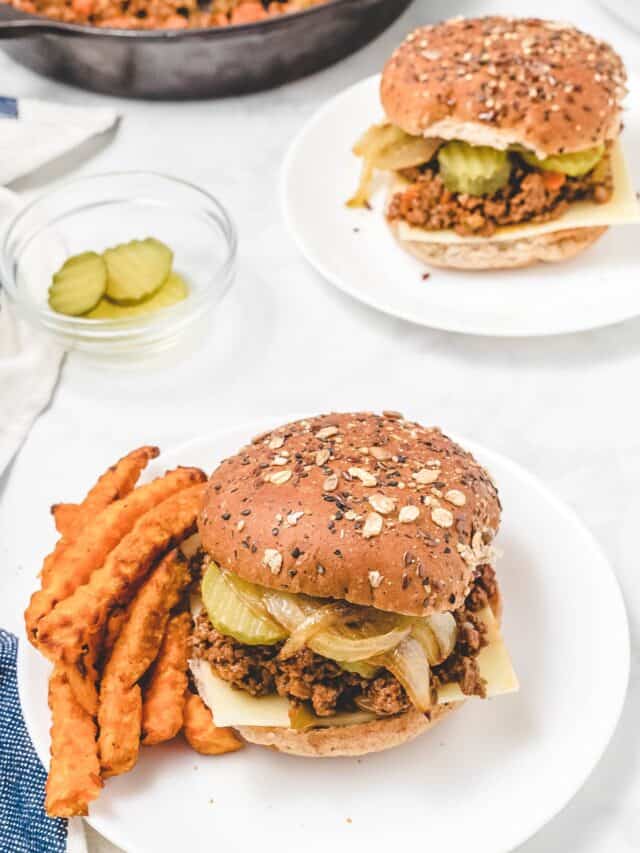 two white plates with healthy sloppy joes over whole wheat buns and sweet potato fries to the side.