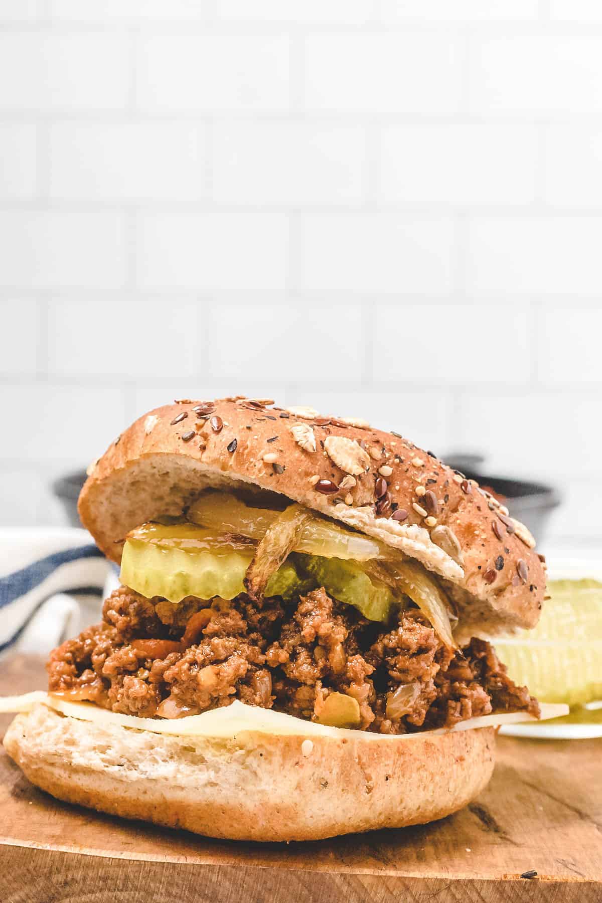whole wheat bun topped with sloppy Joe meat and pickle slices with onions 