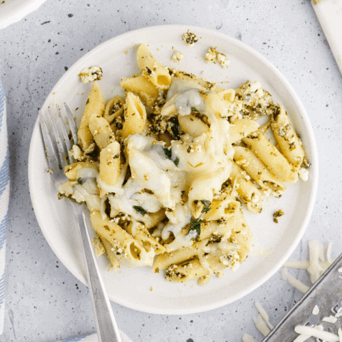 white plate of baked pesto pasta and a fork on the plate