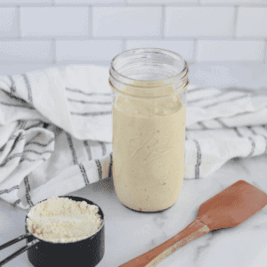 einkorn sourdough starter in a mason jar with a spatula and black measuring cup
