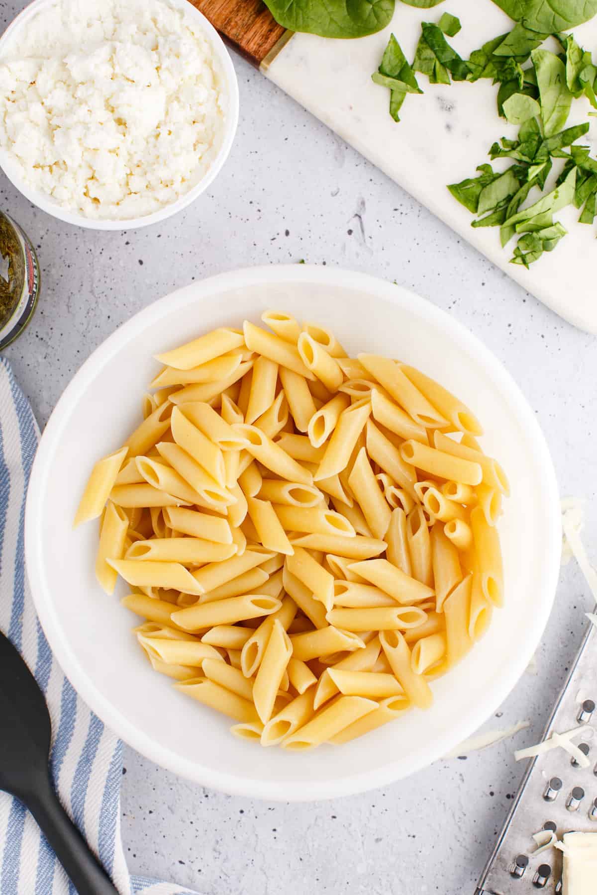 cooked penne pasta in a large white bowl