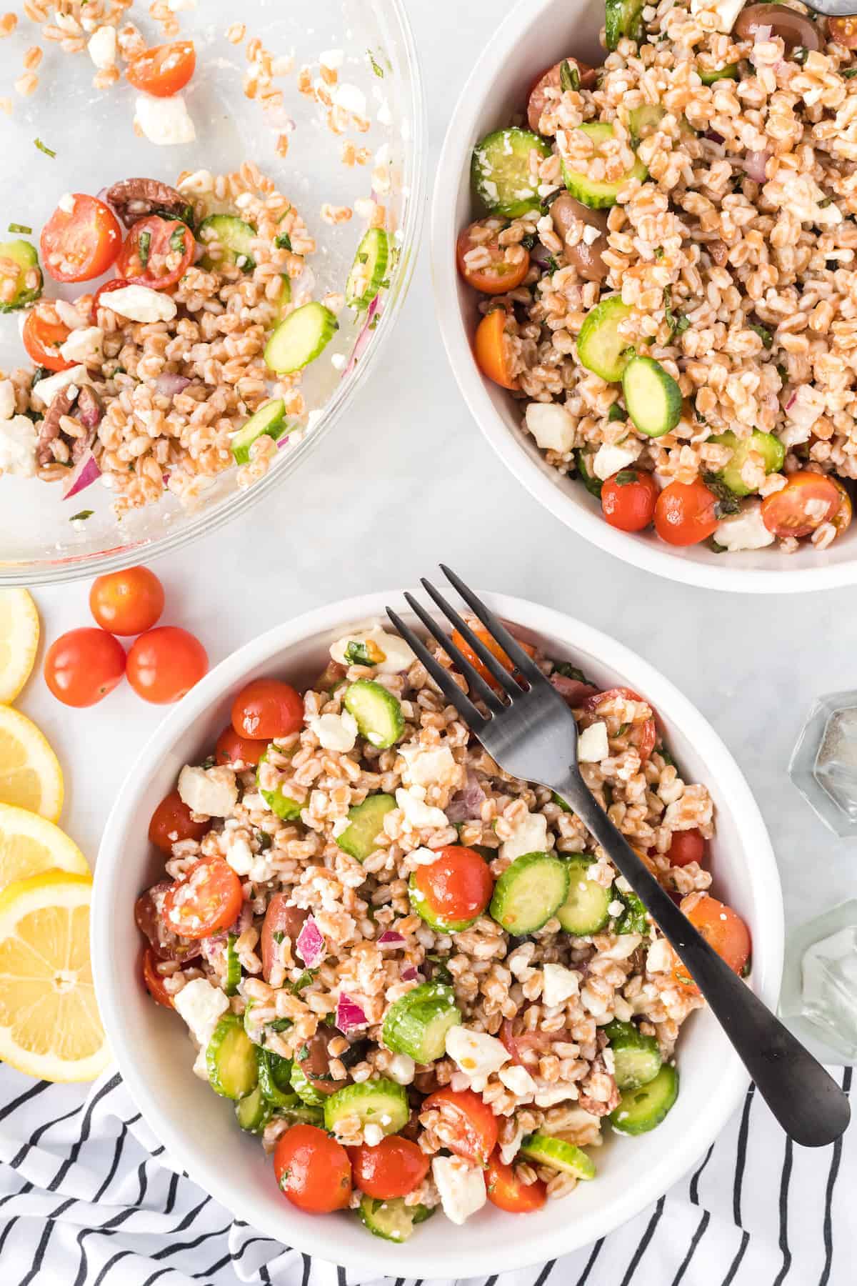 two bowls of farro salad with a serving bowl to the side.