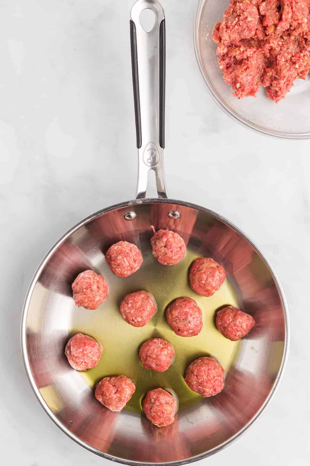 cooking the meatballs in olive oil in a fry pan