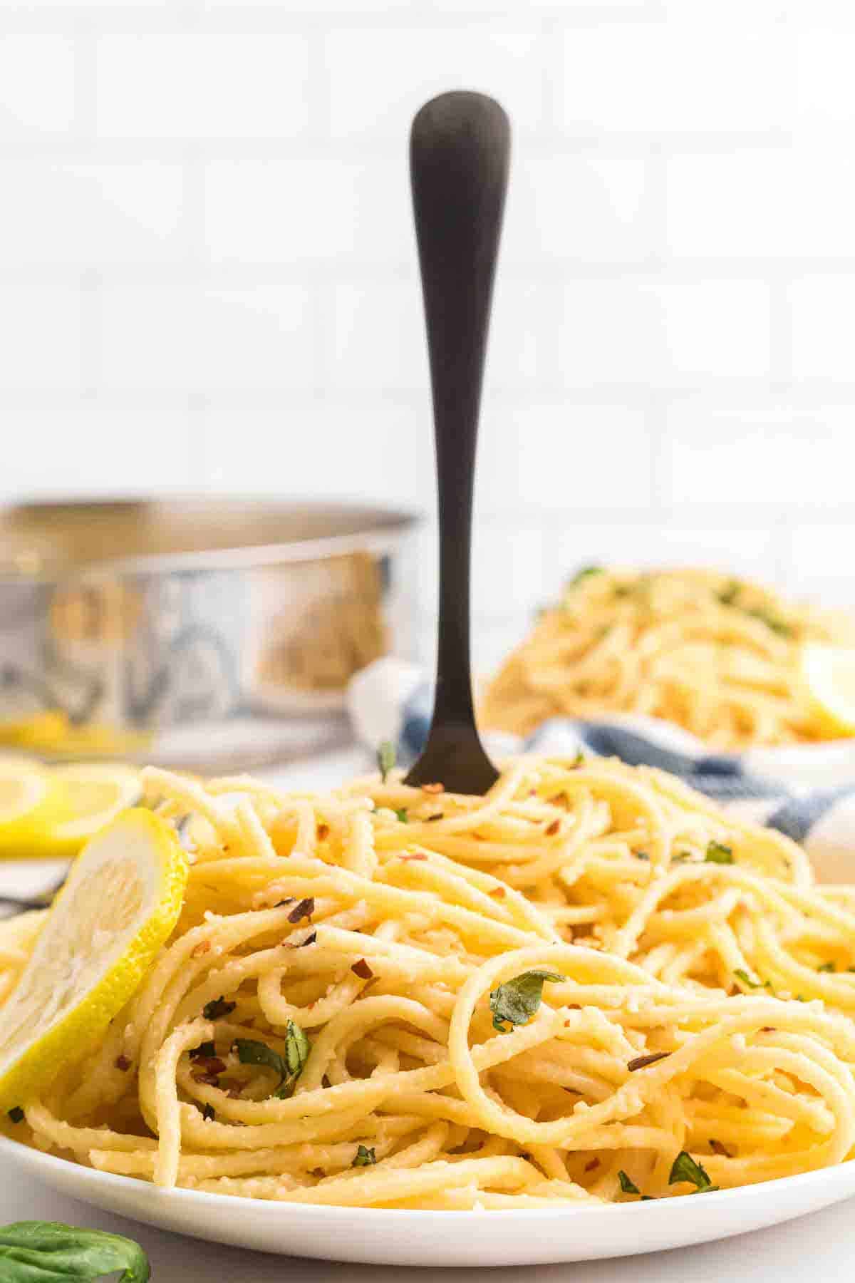 plate of creamy lemon pasta with a black fork sticking in center of the pasta.