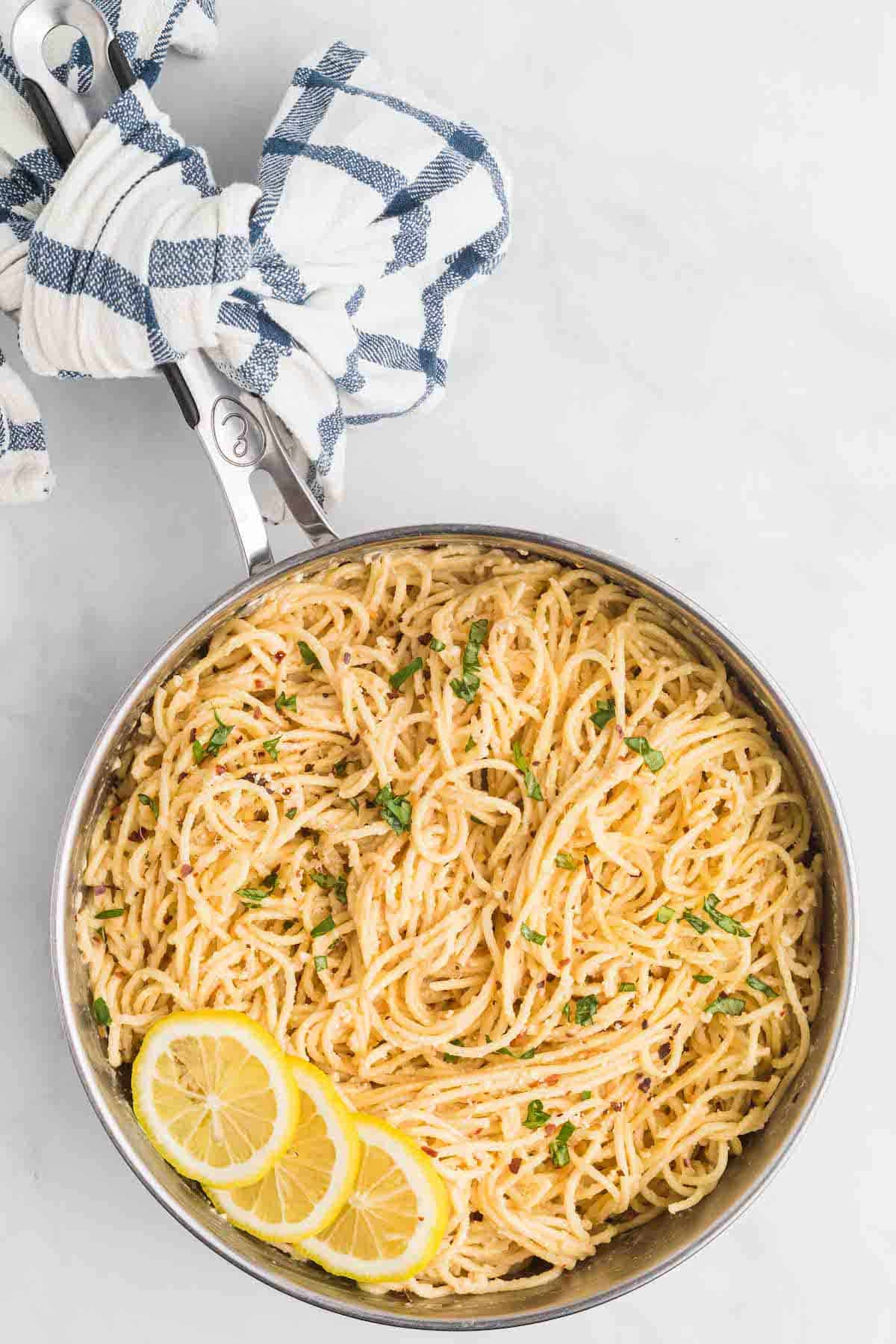 skillet of creamy lemon pasta with fresh herbs on top.