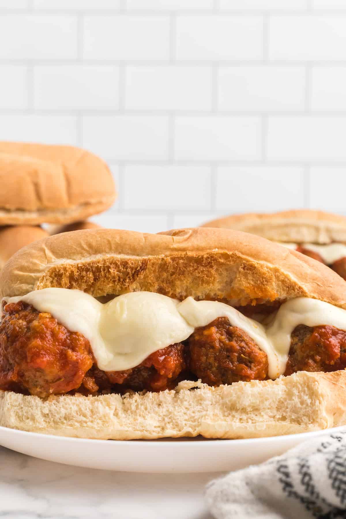 two white plates of the meatball marinara subs with melted mozzarella cheese on top.