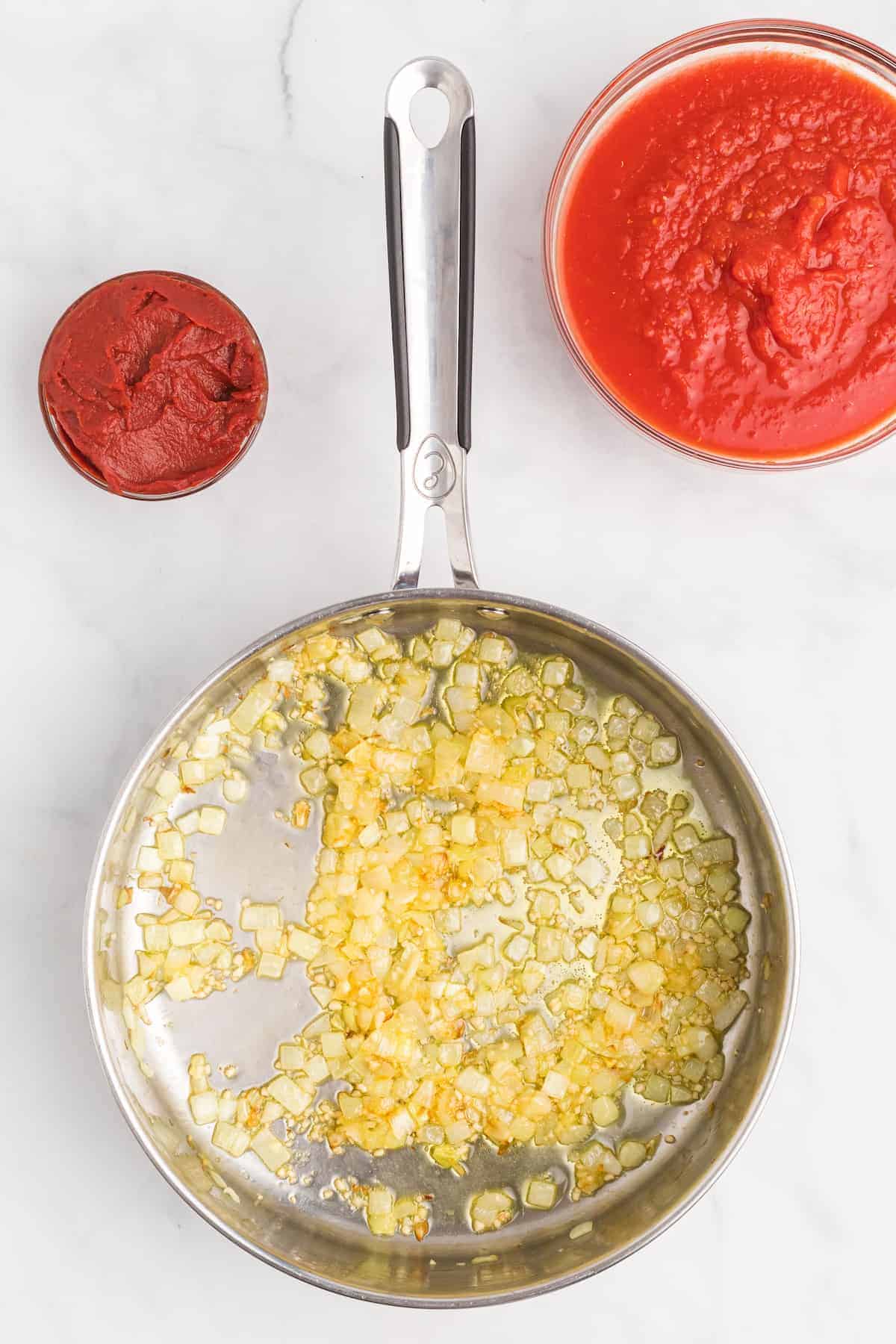 saute pan with olive oil, onions and garlic. And two small bowls with the tomatoes.