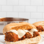 plate with meatball subs and melted mozzarella cheese on top