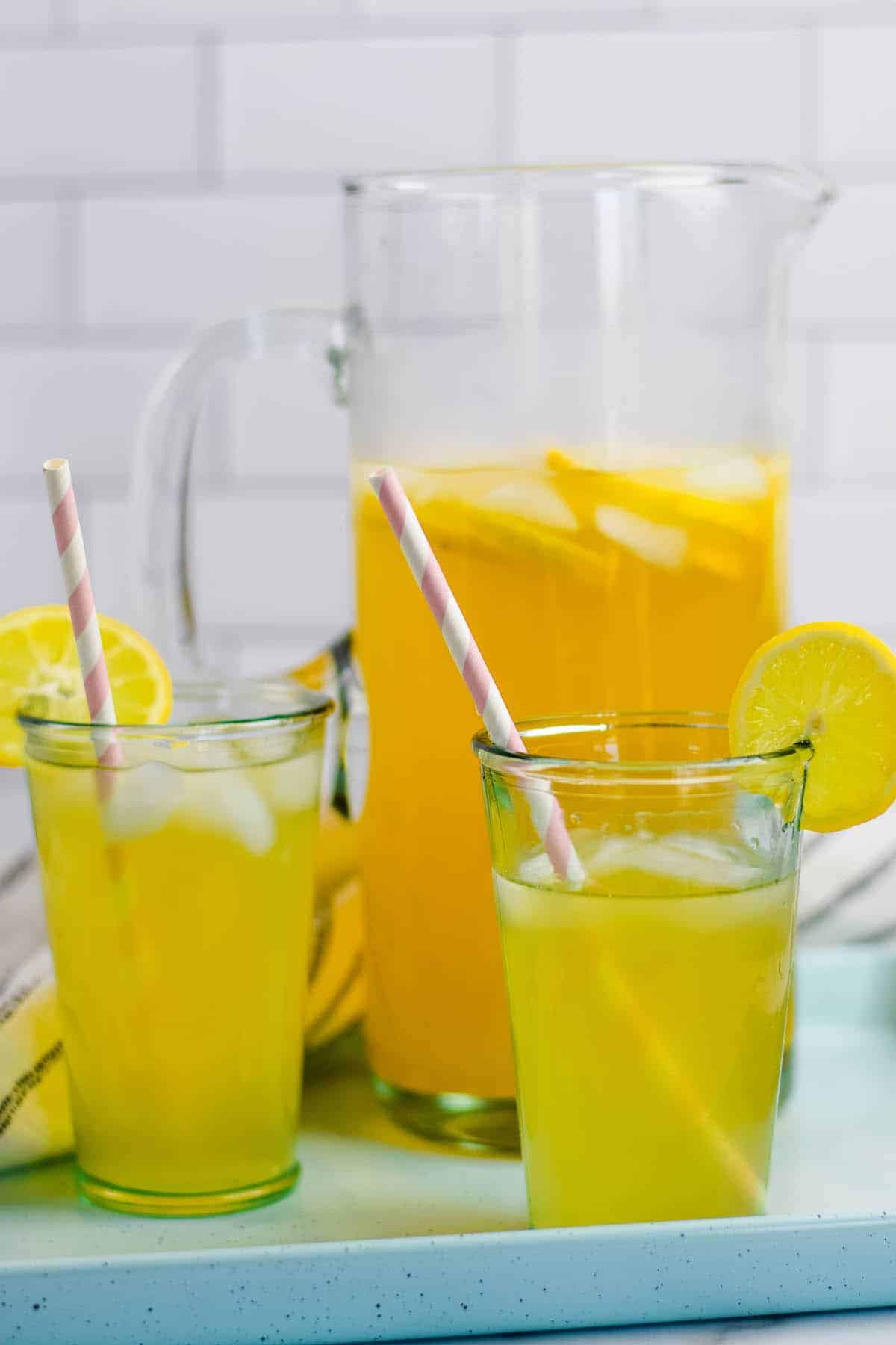 light blue tray with two glasses of healthy lemonade and large pitcher with the lemonade.