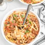 large white bowl of pasta with Bolognese sauce.
