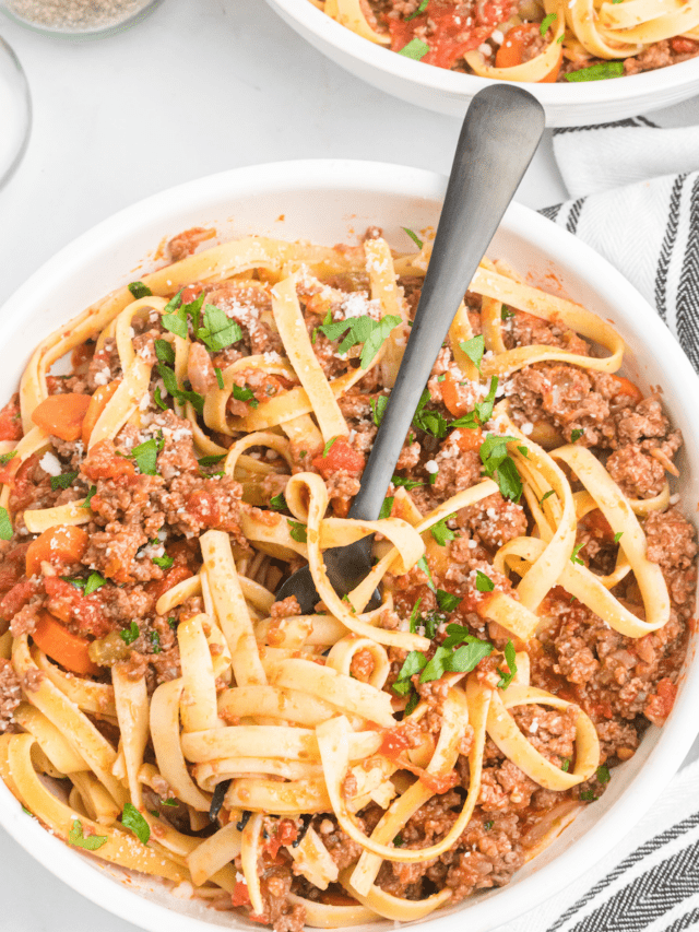 large white bowl of pasta with Bolognese sauce.