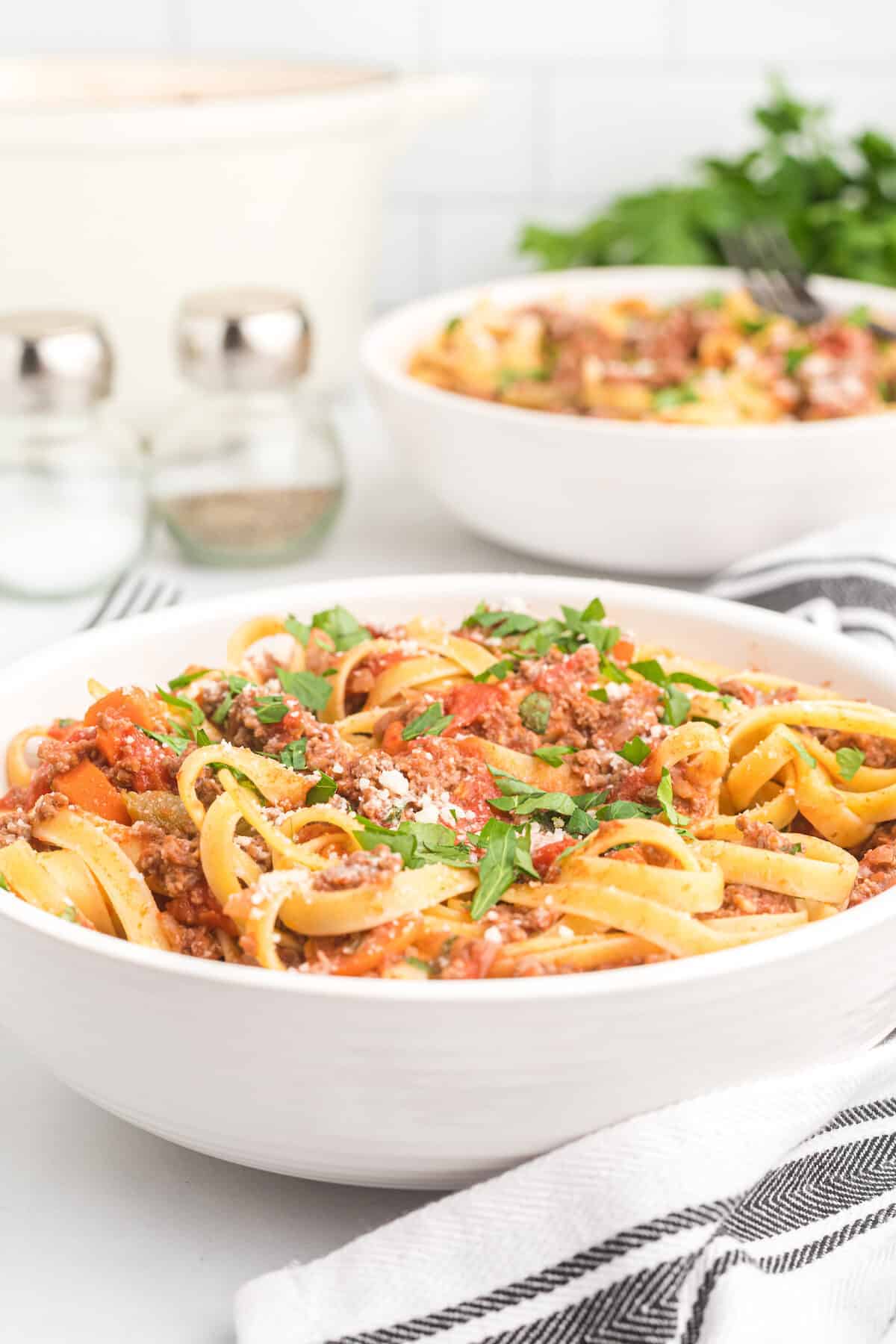 bolognese sauce combined with pasta noodles in a white bowl.