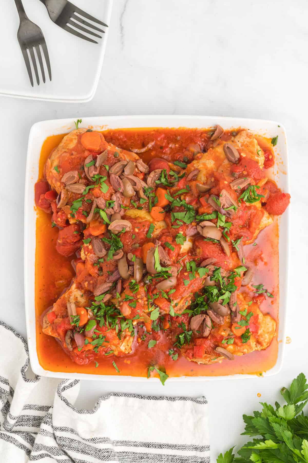 white platter with authentic chicken cacciatore with fresh herbs on top.