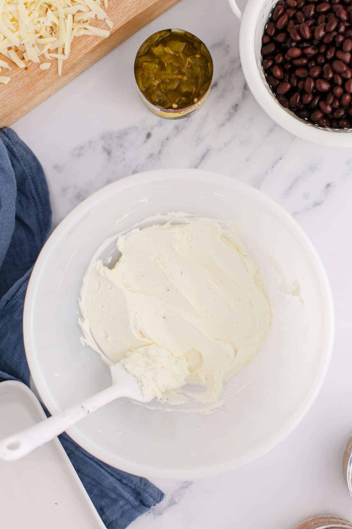 whipped cream cheese in a white bowl with a spatula.