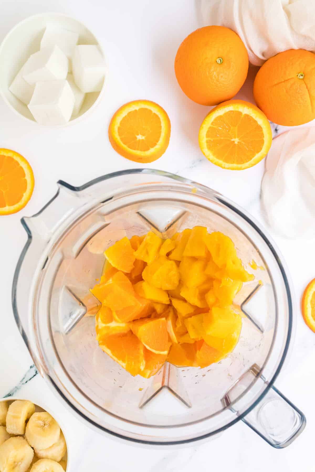 orange slices and mango in the blender with the orange juice.
