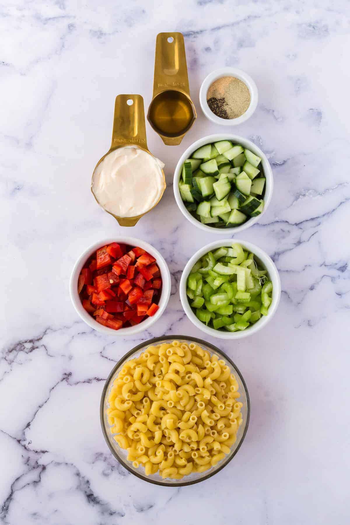 macaroni salad ingredients prepared in in small white bowls.