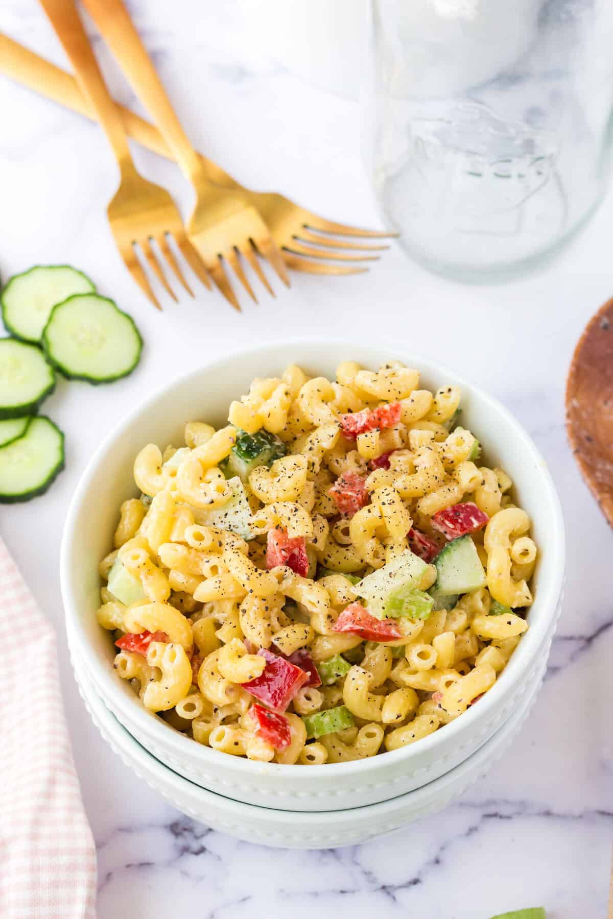 healthy pasta salad in white bowl with gold forks in the back.
