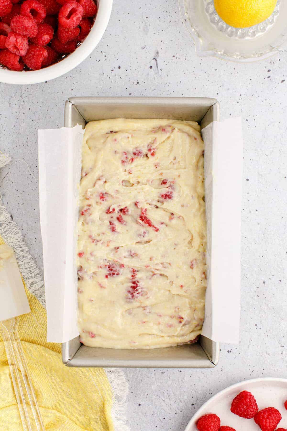 lemon raspberry loaf in a bread pan lined with parchment paper.