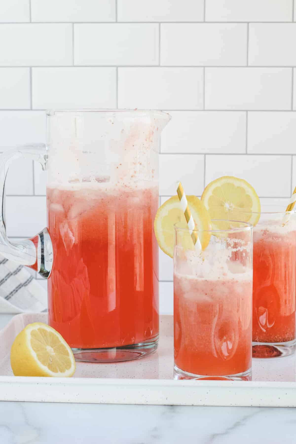 strawberry lemonade in glasses and large glass pitcher. 