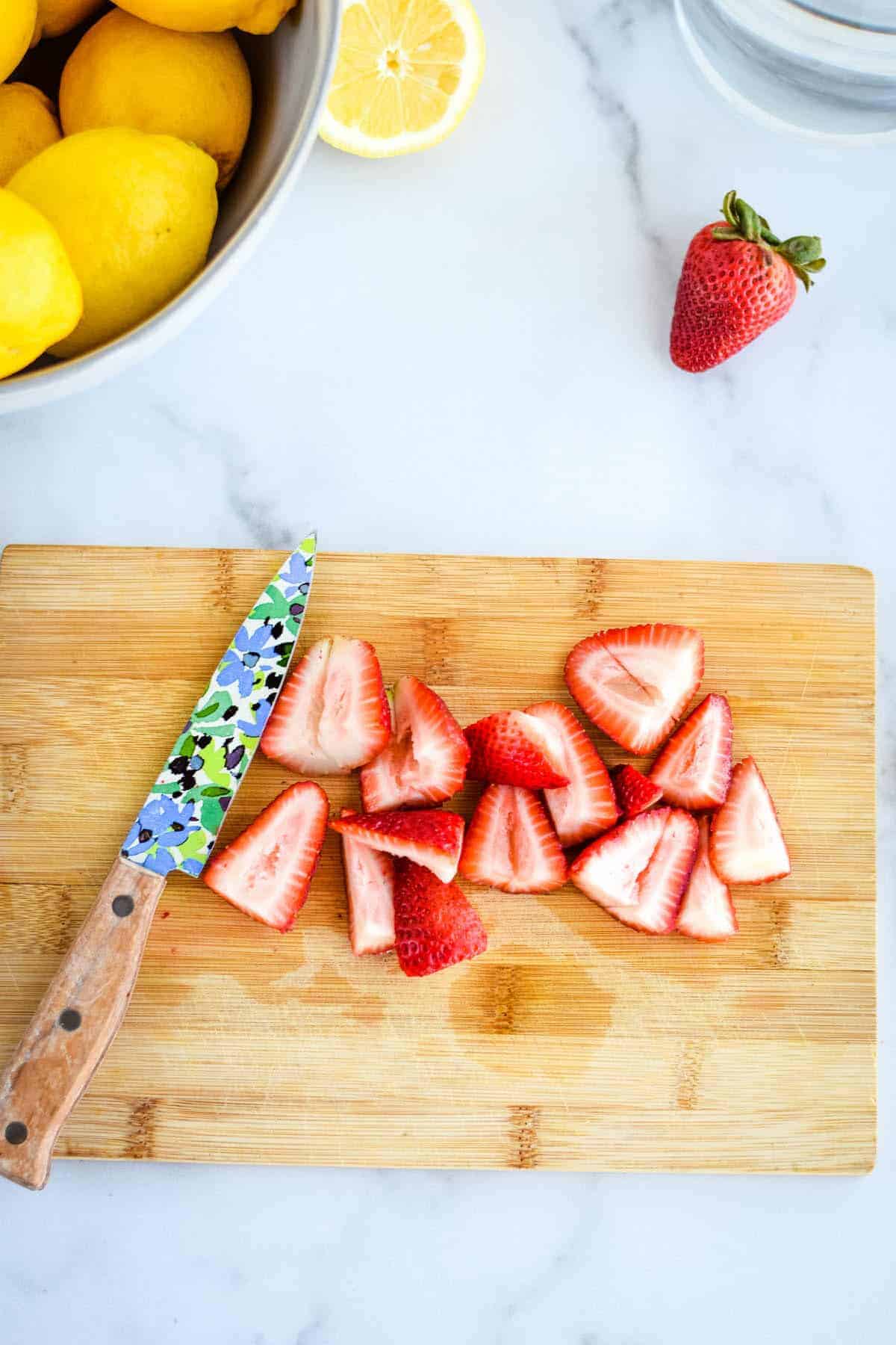 chopping strawberries on a small cutting board.