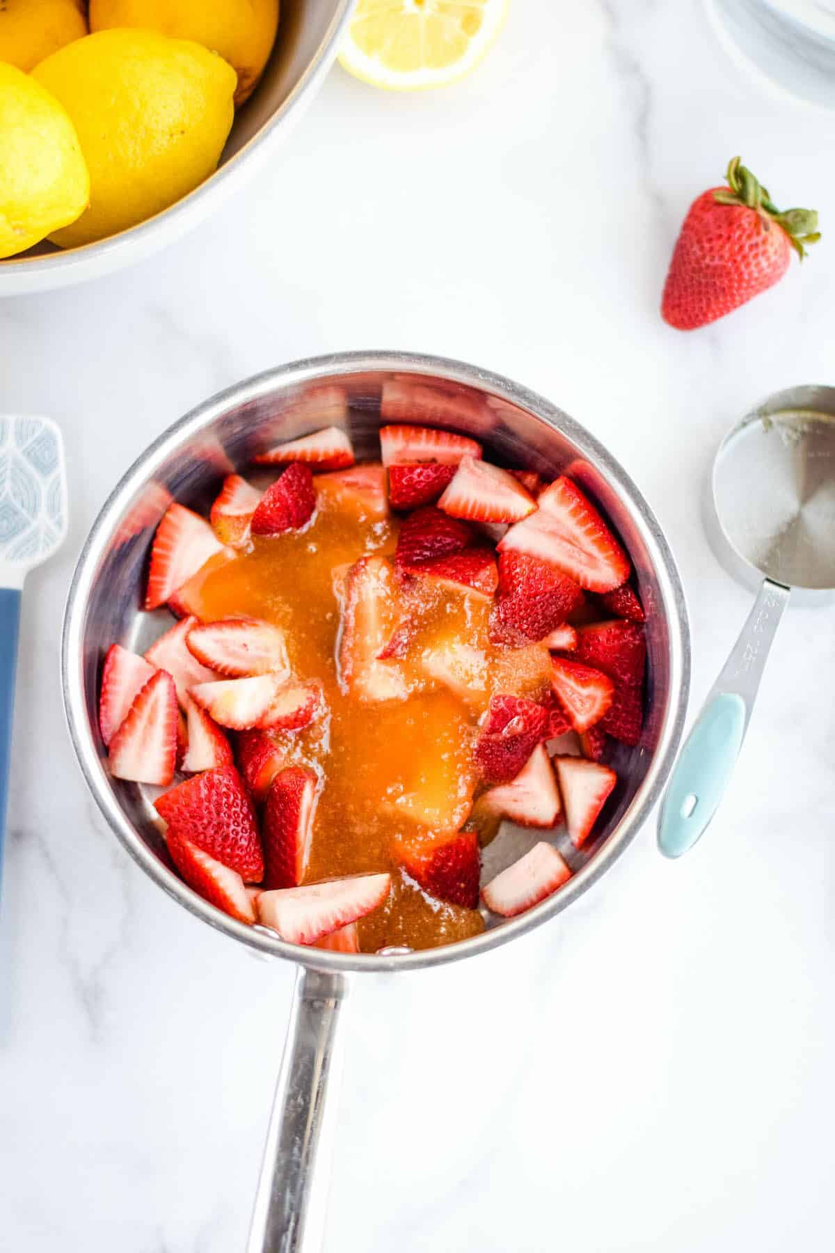 sauce pan with strawberries and honey over top.