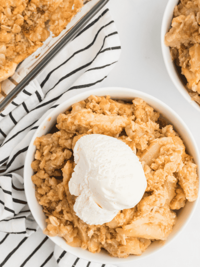 glass baking dish with the apple crisp and two small white bowls paired with the crisp & vanilla ice cream.