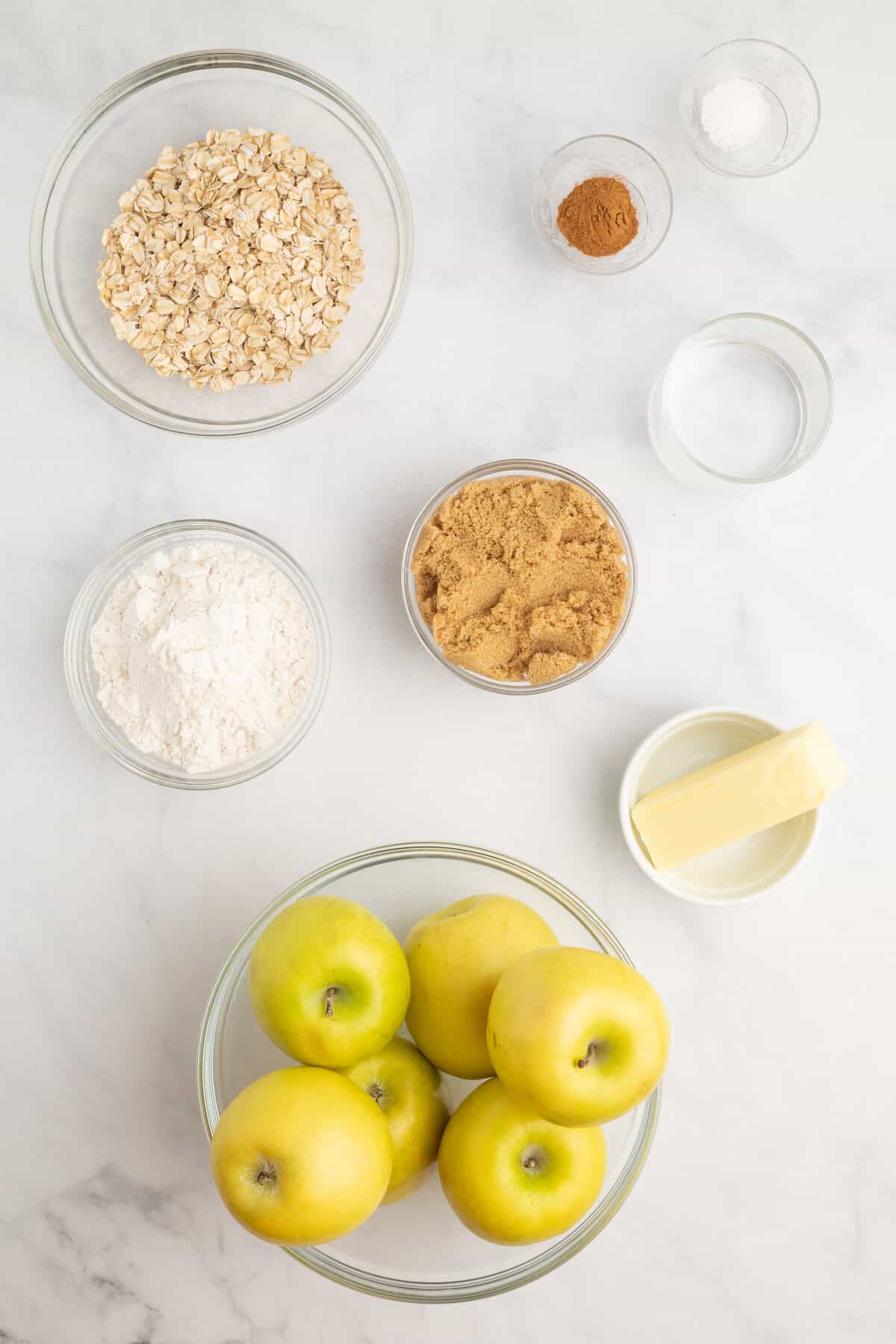 ingredients for the apple crisp in small glass bowls.